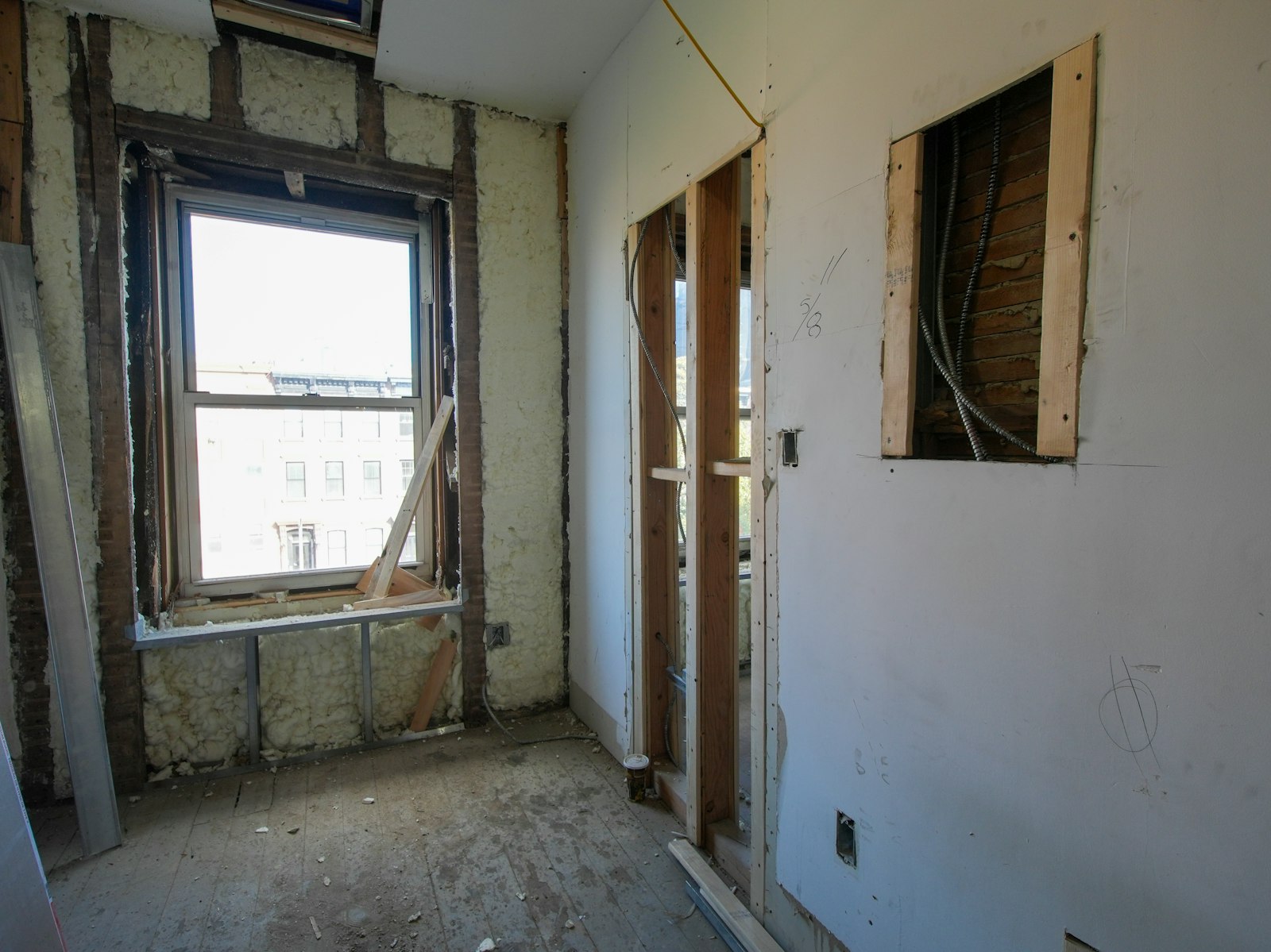 Interior room undergoing renovation with exposed walls and window.